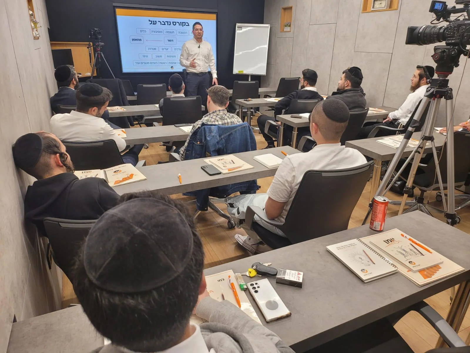 יוסף בן שושן מלמד את קבוצת ההכשרה מול מסך עם נושאי הקורס